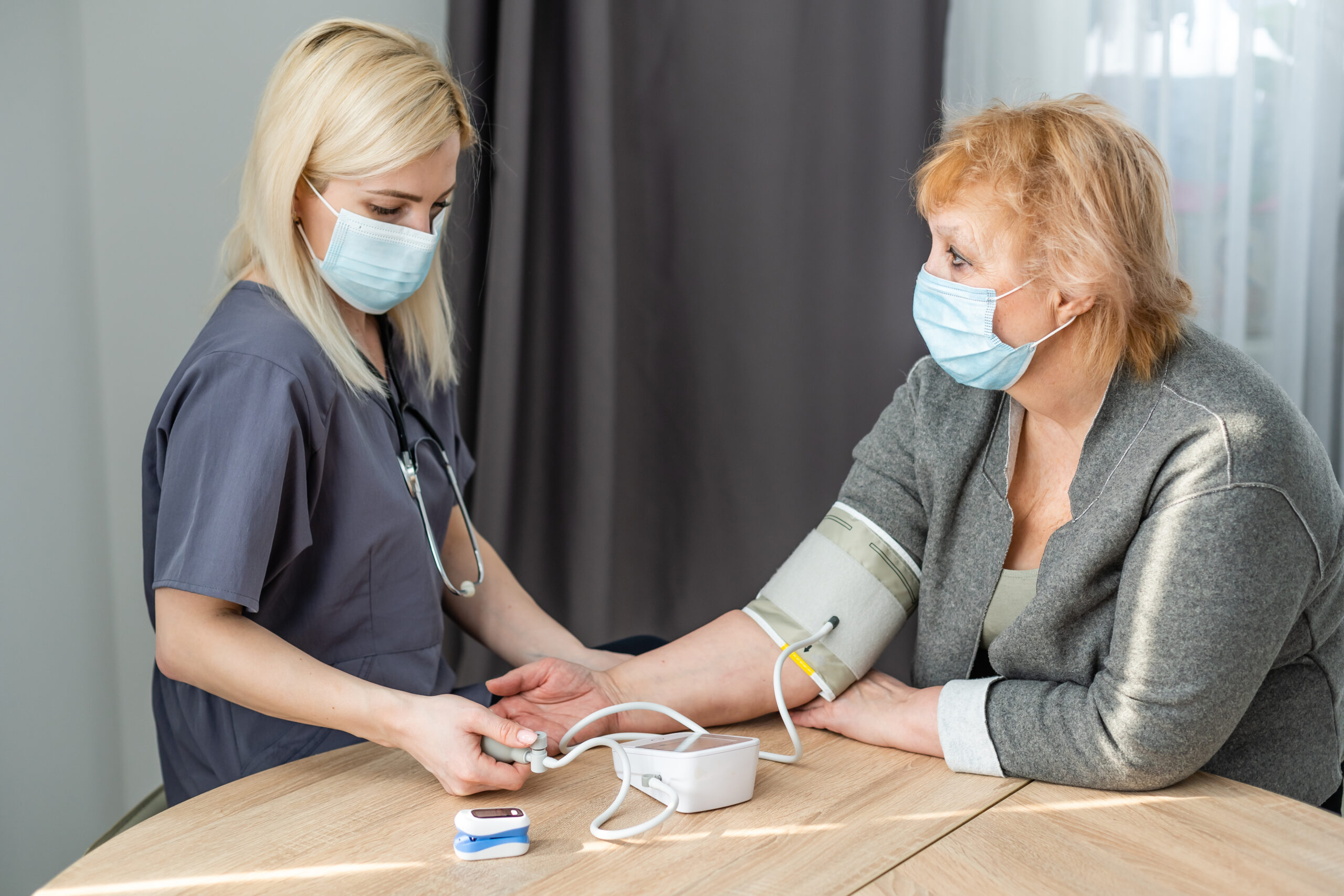 Closeup of nurse checking senior woman blood pressure
